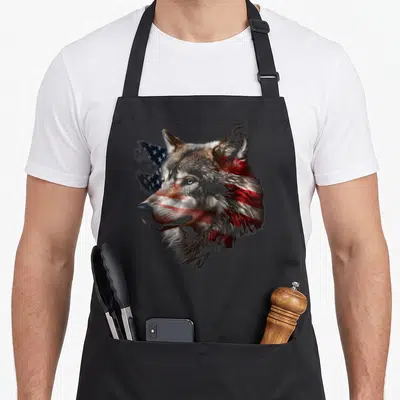 Wolf american flag apron - Realistic wolf head with red white blue flag pattern integrated into fur extending left — shown on a black cotton canvas apron against a white background