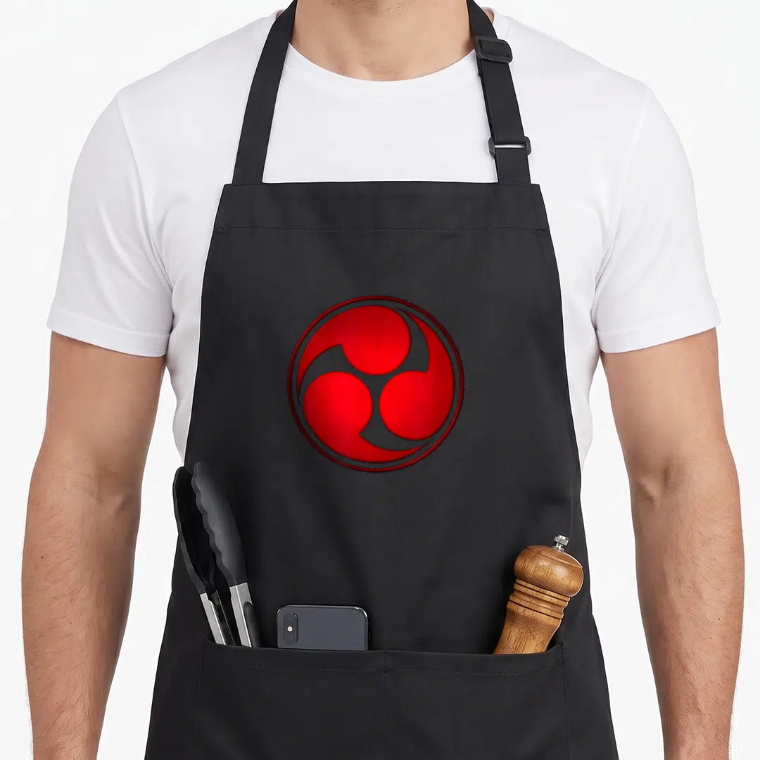 Mitsu japan apron - Red three-comma swirl symbol enclosed in a circle on black background — shown on a black cotton canvas apron against a white background