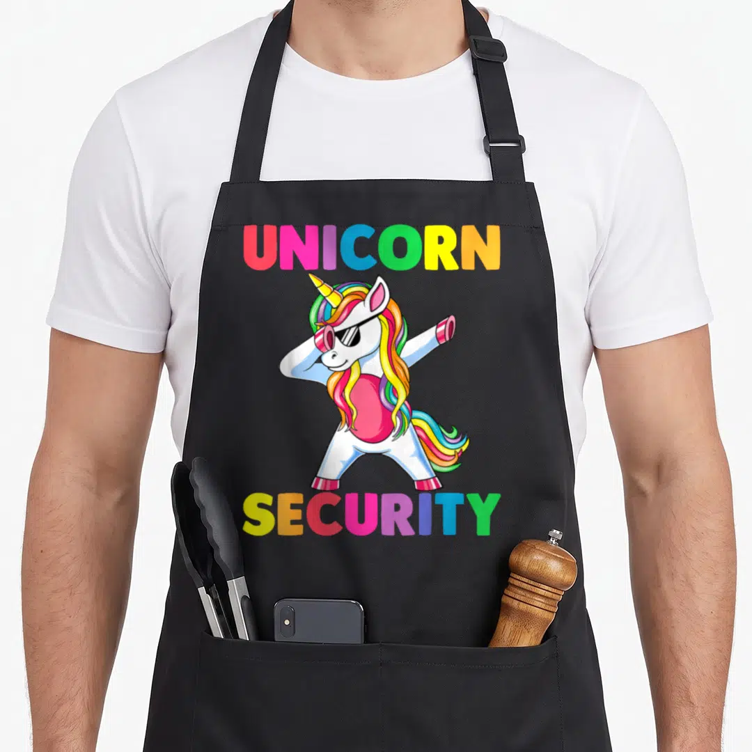 Daughter costume halloween apron - Cartoon unicorn wearing sunglasses dabbing with UNICORN SECURITY text in rainbow — shown on a black cotton canvas apron against a white background