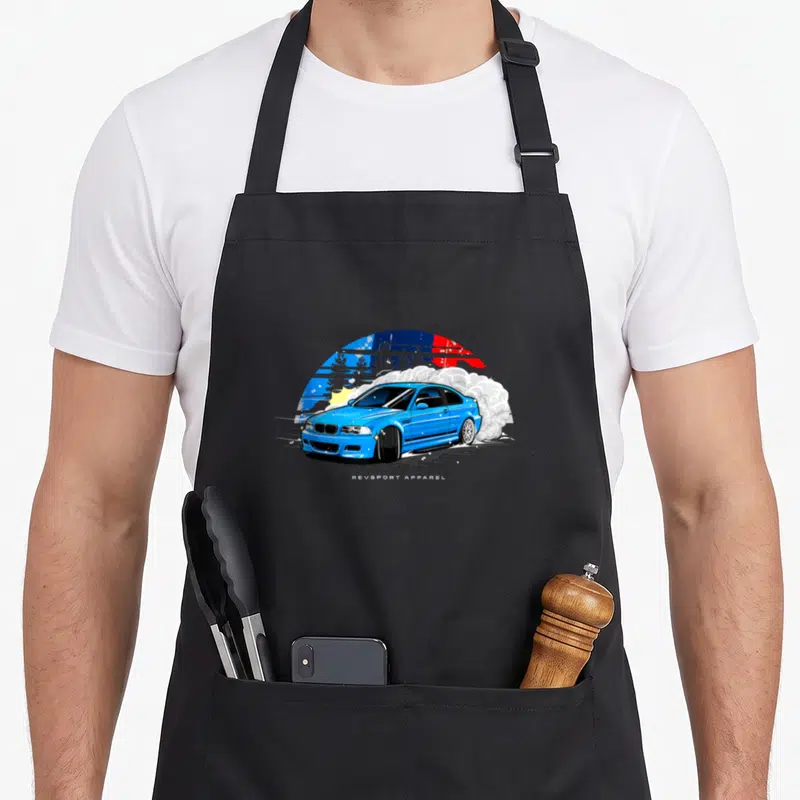 E46 drifting apron - Blue cartoon car drifting with white smoke and colorful sun background — shown on a black cotton canvas apron against a white background