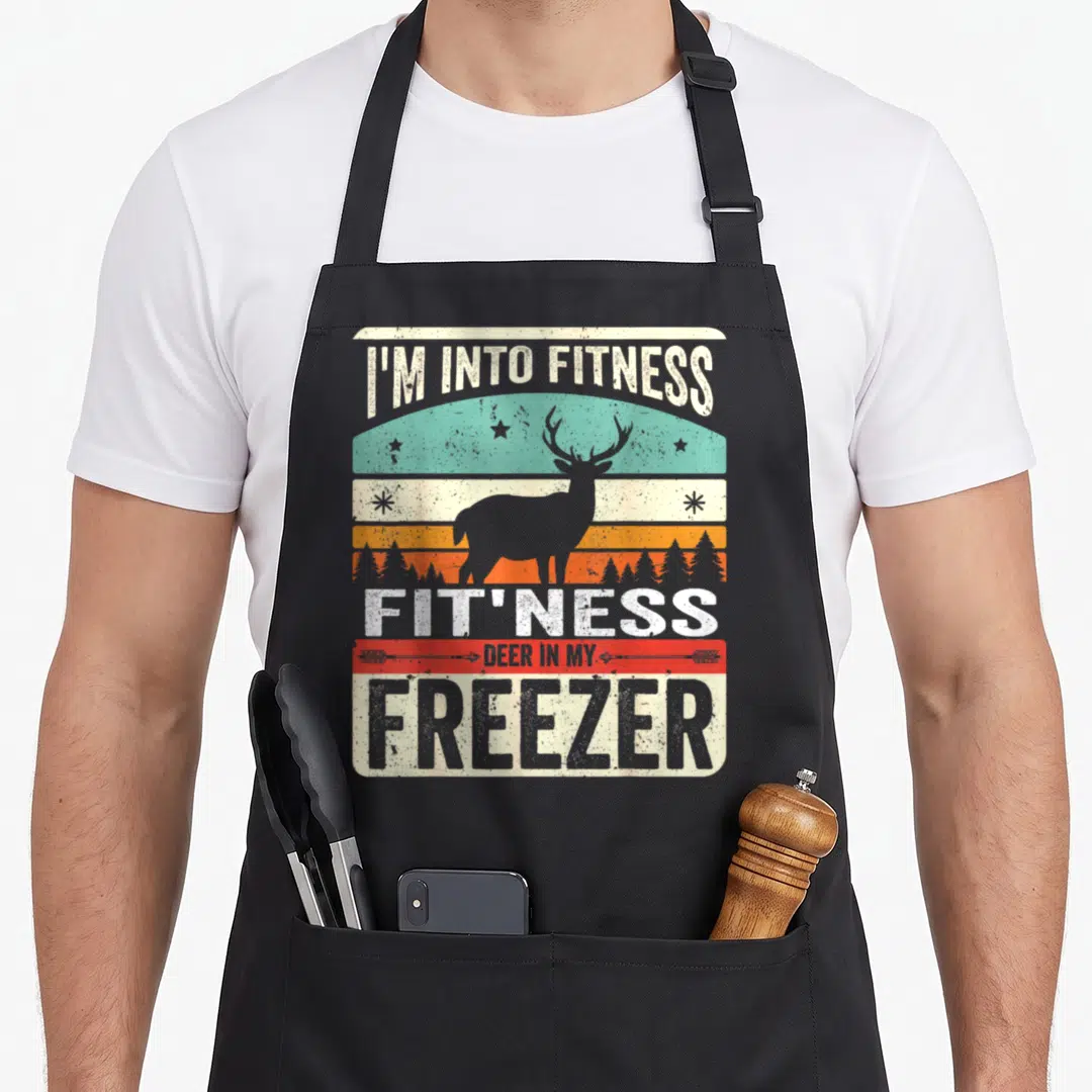 Freezer hunter apron - I'm Into Fitness Fit'ness Deer In My Freezer deer silhouette retro sunset bands — shown on a black cotton canvas apron against a white background