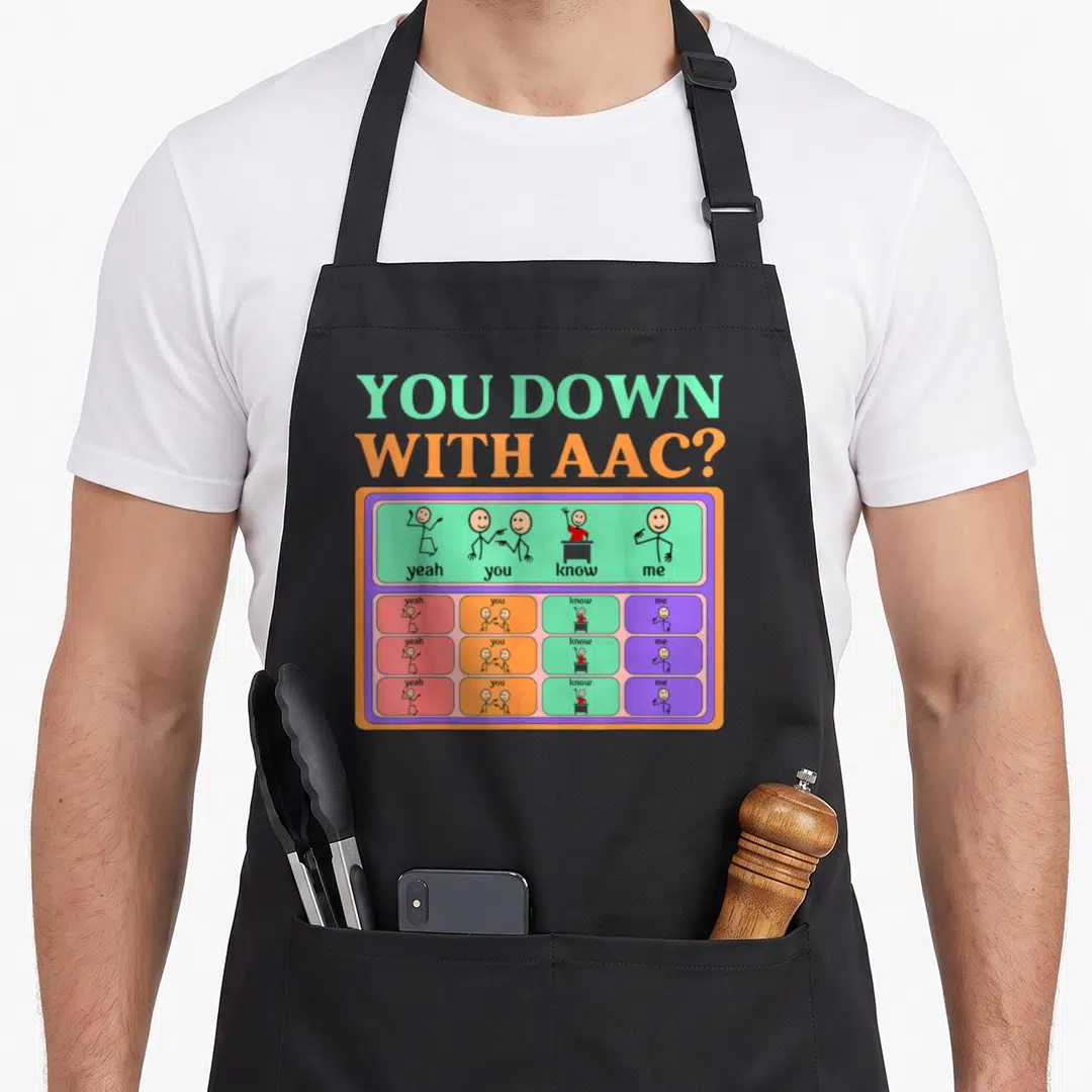 Awareness aac apron - You Down With AAC text above colorful communication board with stick figure icons and three rows — shown on a black cotton canvas apron against a white background