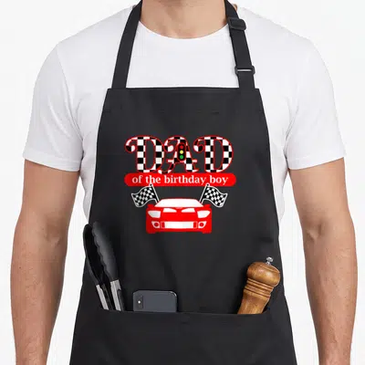 Car daddy apron - DAD of the birthday boy with red race car and checkered flags — shown on a black cotton canvas apron against a white background