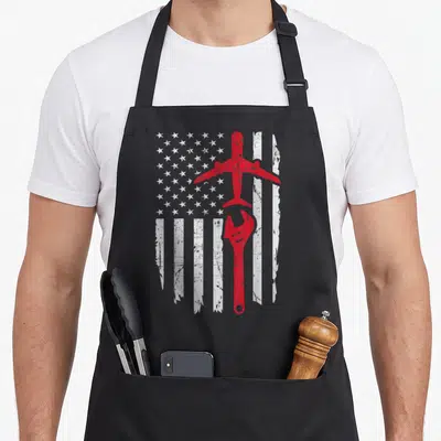Mechanic airplane apron - Distressed white USA flag with red airplane and wrench vertically centered — shown on a black cotton canvas apron against a white background