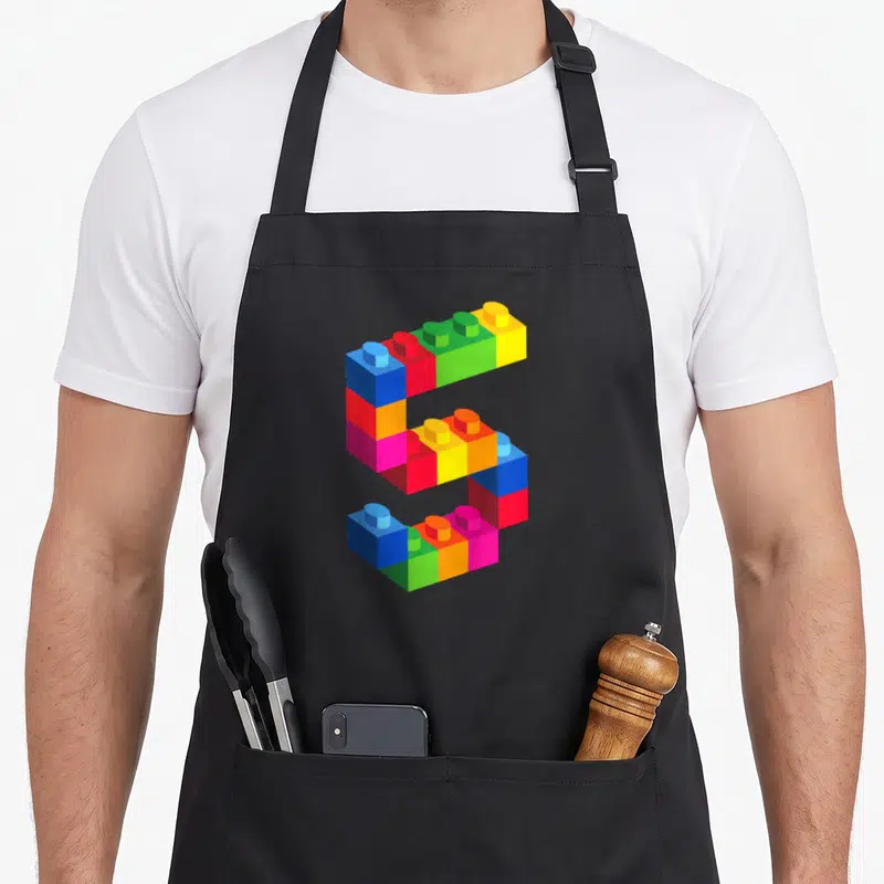Brick block & apron - Number 5 constructed from blue red green yellow orange pink toy bricks — shown on a black cotton canvas apron against a white background