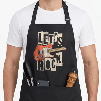 Rock guitar apron - Retro orange electric guitar separating LET'S ROCK text in halftone dot pattern — shown on a black cotton canvas apron against a white background