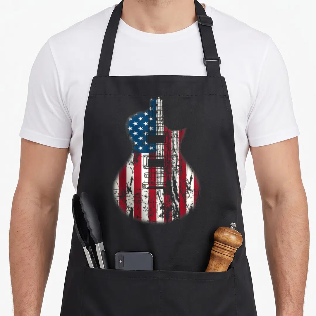 Musician american flag apron - Distressed electric guitar silhouette filled with red white and blue USA flag pattern — shown on a black cotton canvas apron against a white background