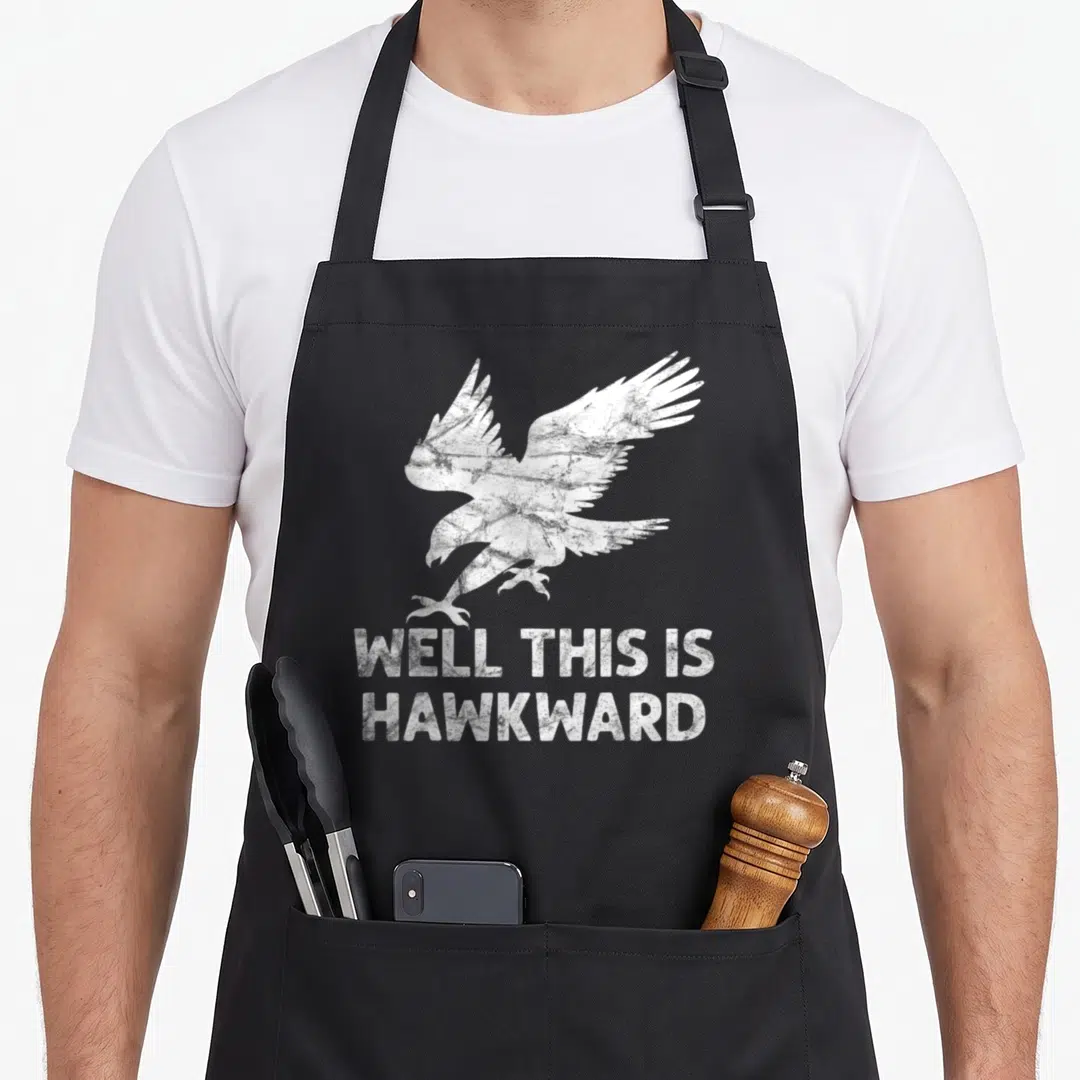 Well bird apron - Distressed white hawk above stacked text reading well this is hawkward — shown on a black cotton canvas apron against a white background