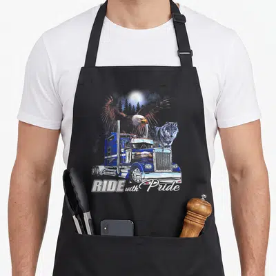 Ride eagles grill apron - Blue semi-truck with bald eagle and wolf behind white RIDE with Pride text — shown on a black cotton canvas apron against a white background