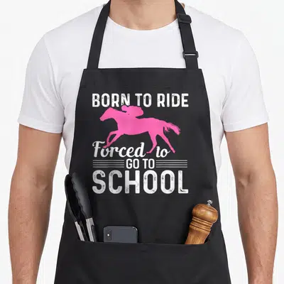 Horseback horse apron - Pink horse silhouette with white distressed text Born to Ride Forced to Go to School — shown on a black cotton canvas apron against a white background