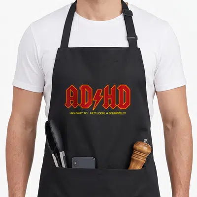 Hey squirrel aprons - Red ADHD text with yellow lightning bolt and slogan highway to hey look a squirrel — shown on a black cotton canvas apron against a white background