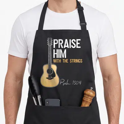 Praise string christian apron - Acoustic guitar illustration next to stacked white and yellow text PRAISE HIM — shown on a black cotton canvas apron against a white background