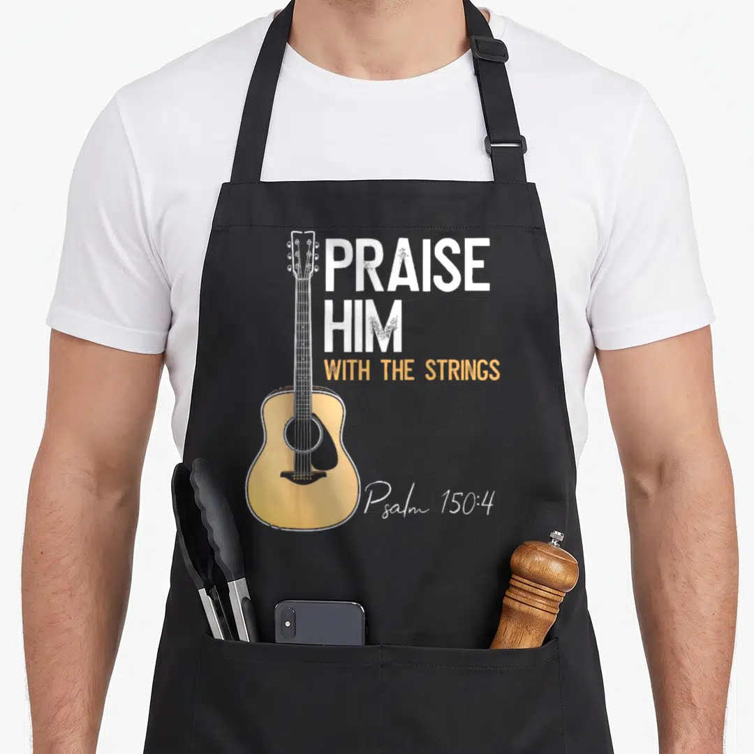 Praise string christian apron - Acoustic guitar illustration next to stacked white and yellow text PRAISE HIM — shown on a black cotton canvas apron against a white background