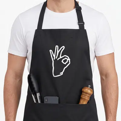 Boredkoalas meme apron - White line art hand making ok sign on black bib apron — shown on a black cotton canvas apron against a white background
