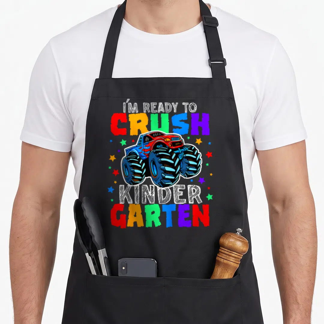Crush kindergarten truck apron - Monster truck graphic with I'M READY TO CRUSH KINDER GARTEN text and multi-colored — shown on a black cotton canvas apron against a white background