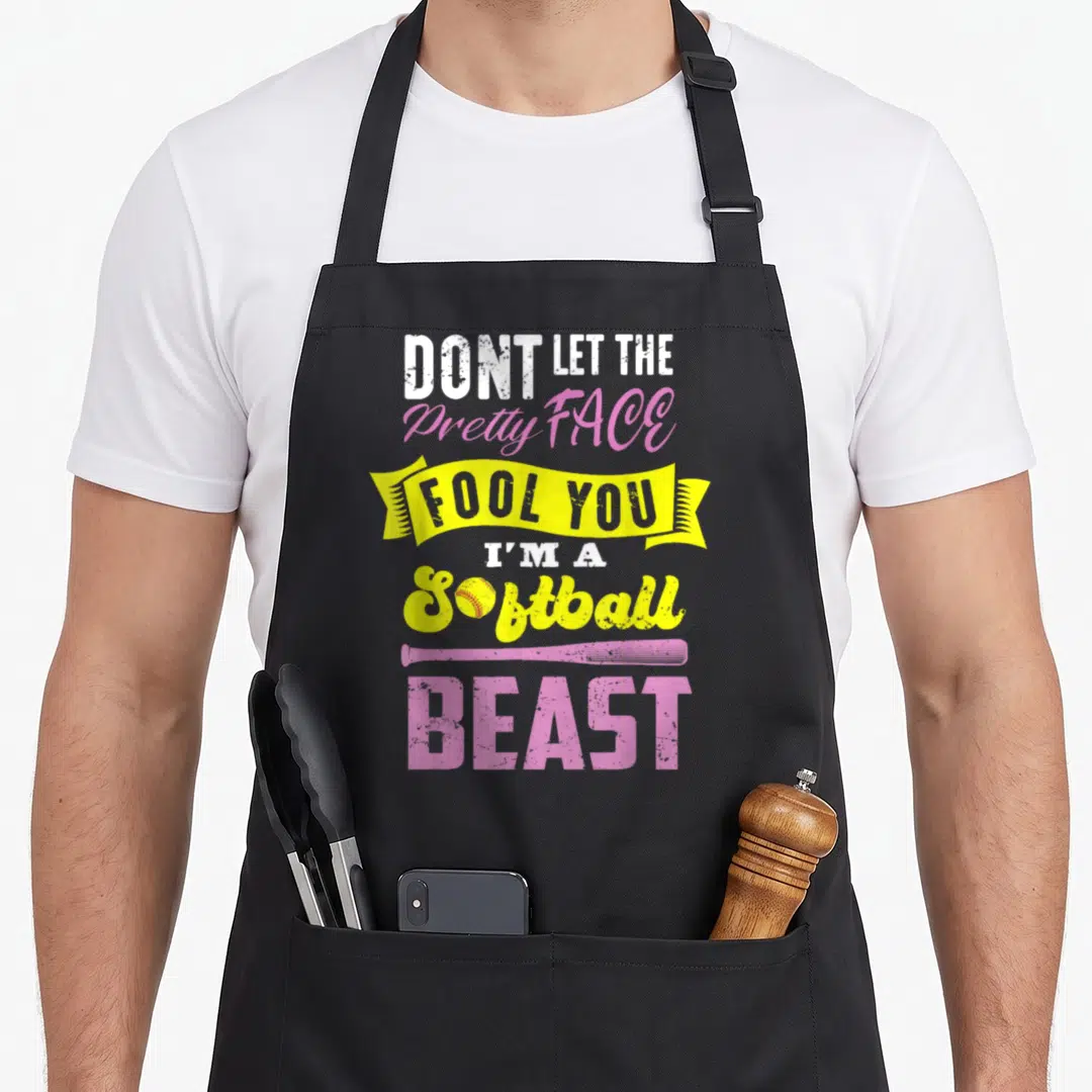 Fastpitch game aprons - DONT LET THE Pretty FACE FOOL YOU I'M A Softball BEAST text with bat and ball graphics in pink — shown on a black cotton canvas apron against a white background