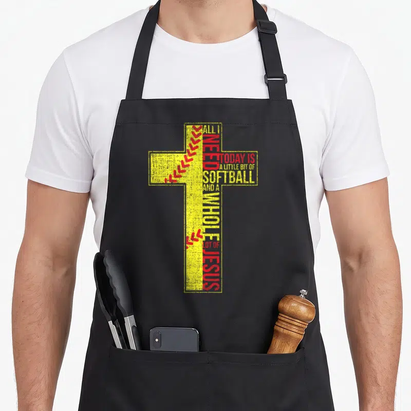 Softball christian apron - Yellow cross with red softball stitches and text 'All I Need Today Is Softball And A Whole — shown on a black cotton canvas apron against a white background