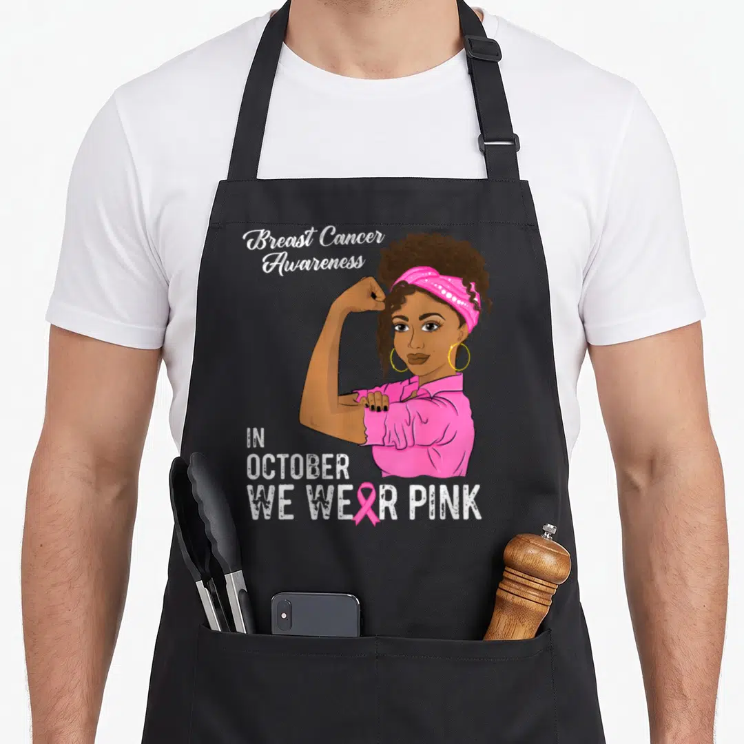 Vintage october breast cancer awareness aprons - Cartoon woman flexing arm with Breast Cancer Awareness text and pink — shown on a black cotton canvas apron against a white background