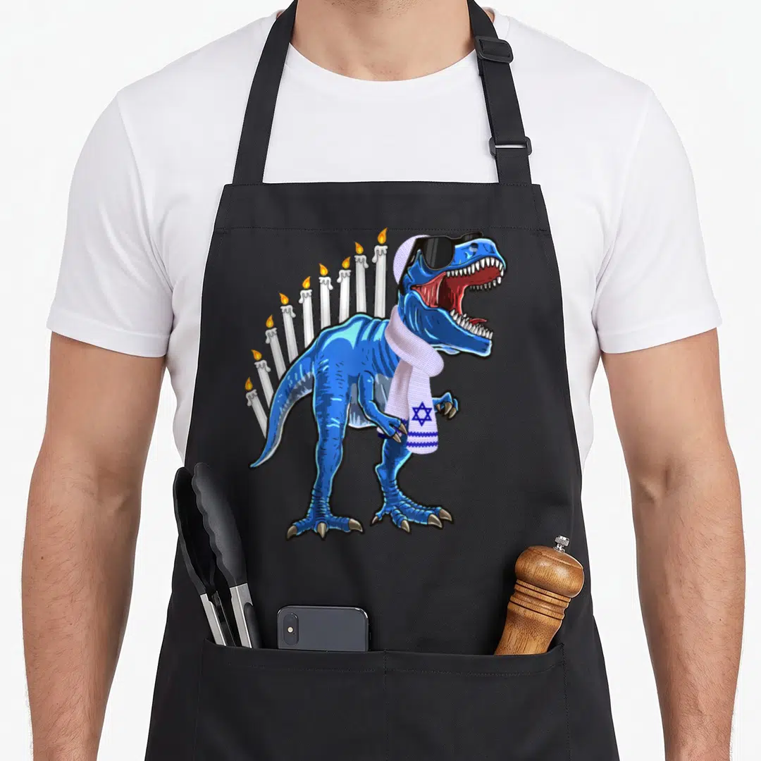 Menorasaurus hanukkah apron - Blue T-Rex with sunglasses and Star of David scarf in front of nine candles — shown on a black cotton canvas apron against a white background