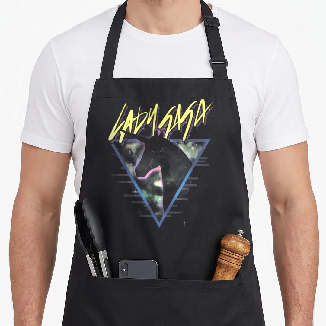 Gaga unicorn apron - LADY SASA yellow text over blue triangle galaxy unicorn silhouette — shown on a black cotton canvas apron against a white background