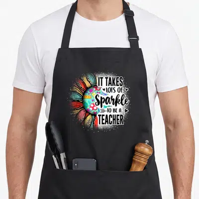 Lot sunflower apron - Colorful sphere and teacher quote on black bib apron — shown on a black cotton canvas apron against a white background