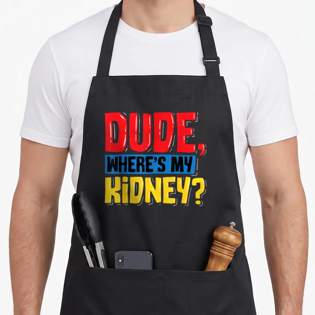 Dude organ apron - Cartoon text DUDE WHERE'S MY KIDNEY in red blue yellow and black — shown on a black cotton canvas apron against a white background