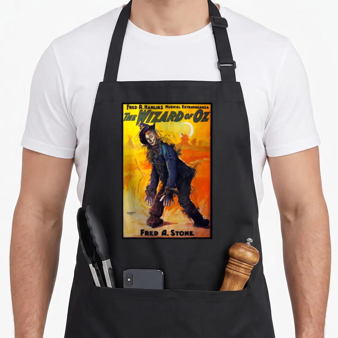 Poster scarecrow apron - Retro poster of Fred A. Stone as Scarecrow with yellow and orange background and crescent moon — shown on a black cotton canvas apron against a white background