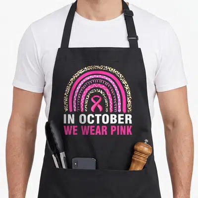Leopard breast cancer awareness aprons - Rainbow with leopard print bands, pink ribbon, and IN OCTOBER WE WEAR PINK text — shown on a black cotton canvas apron against a white background