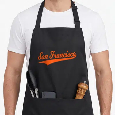 Varsity san francisco apron - Orange script text San Francisco with swoosh underline on grey background — shown on a black cotton canvas apron against a white background