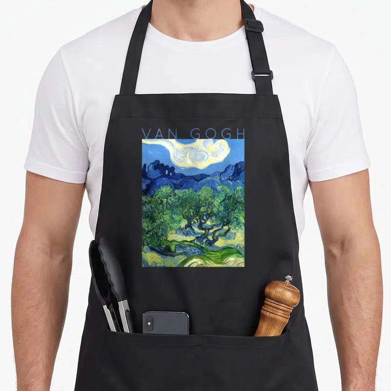 Van tree aprons - Blue text reading Van Gogh above a landscape with green olive trees and yellow sky — shown on a black cotton canvas apron against a white background