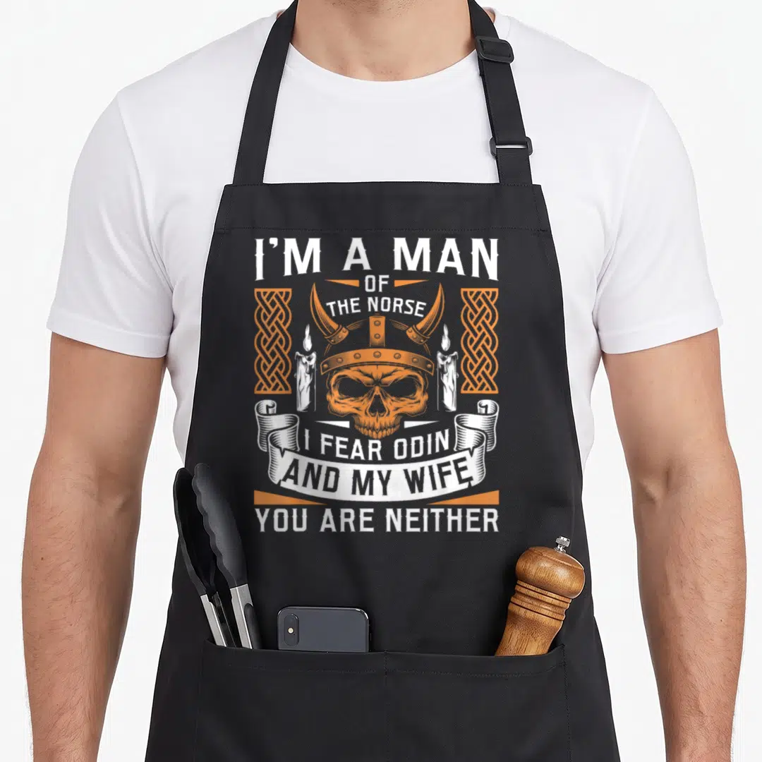 Fear wife apron - Orange skull in horned helmet flanked by candles and knotwork with white Norse text — shown on a black cotton canvas apron against a white background