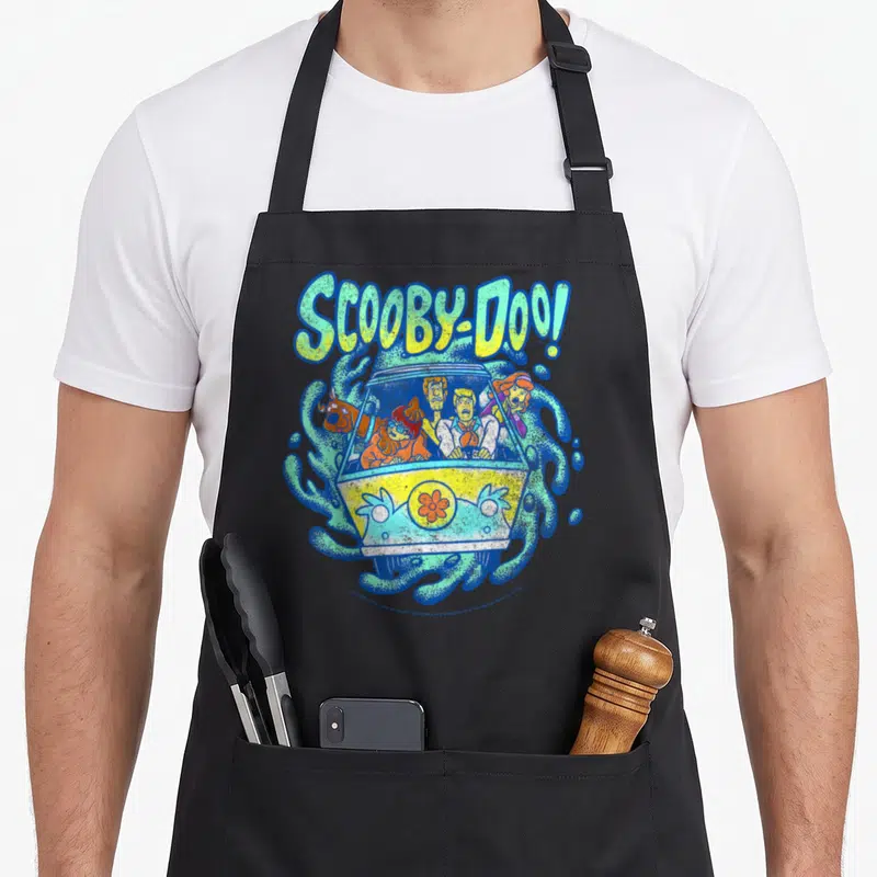 Portal machine apron - Scooby-Doo Mystery Machine cartoon illustration with swirling blue and green patterns — shown on a black cotton canvas apron against a white background