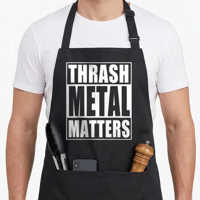 Metal thrash apron - White stacked text THRASH METAL MATTERS inside a rectangular border on grey background — shown on a black cotton canvas apron against a white background