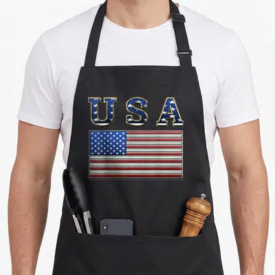 State american flag apron - USA text filled with stars above a realistic red white and blue American flag — shown on a black cotton canvas apron against a white background