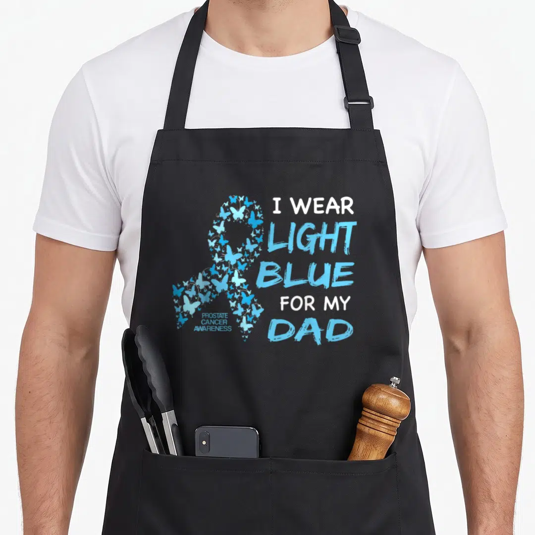Light prostate cancer awareness apron - Light blue butterfly awareness ribbon with stacked text reading I WEAR LIGHT — shown on a black cotton canvas apron against a white background