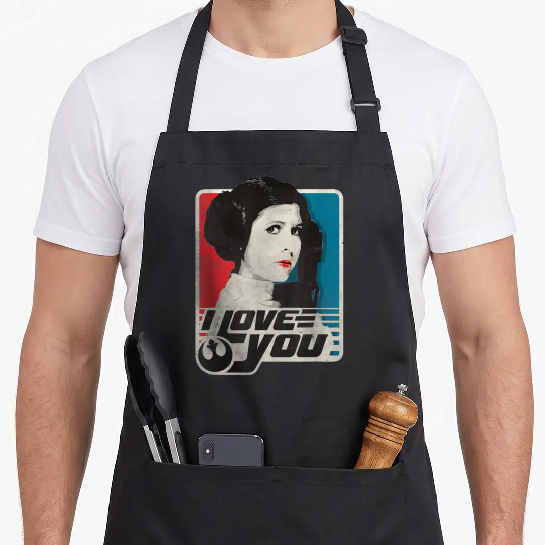 Rebel i love stars apron - Princess Leia portrait on red blue background with I LOVE YOU text and Rebel symbol — shown on a black cotton canvas apron against a white background