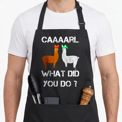 Lamas h apron - Two llamas facing each other with hats under CAAAARL text — shown on a black cotton canvas apron against a white background