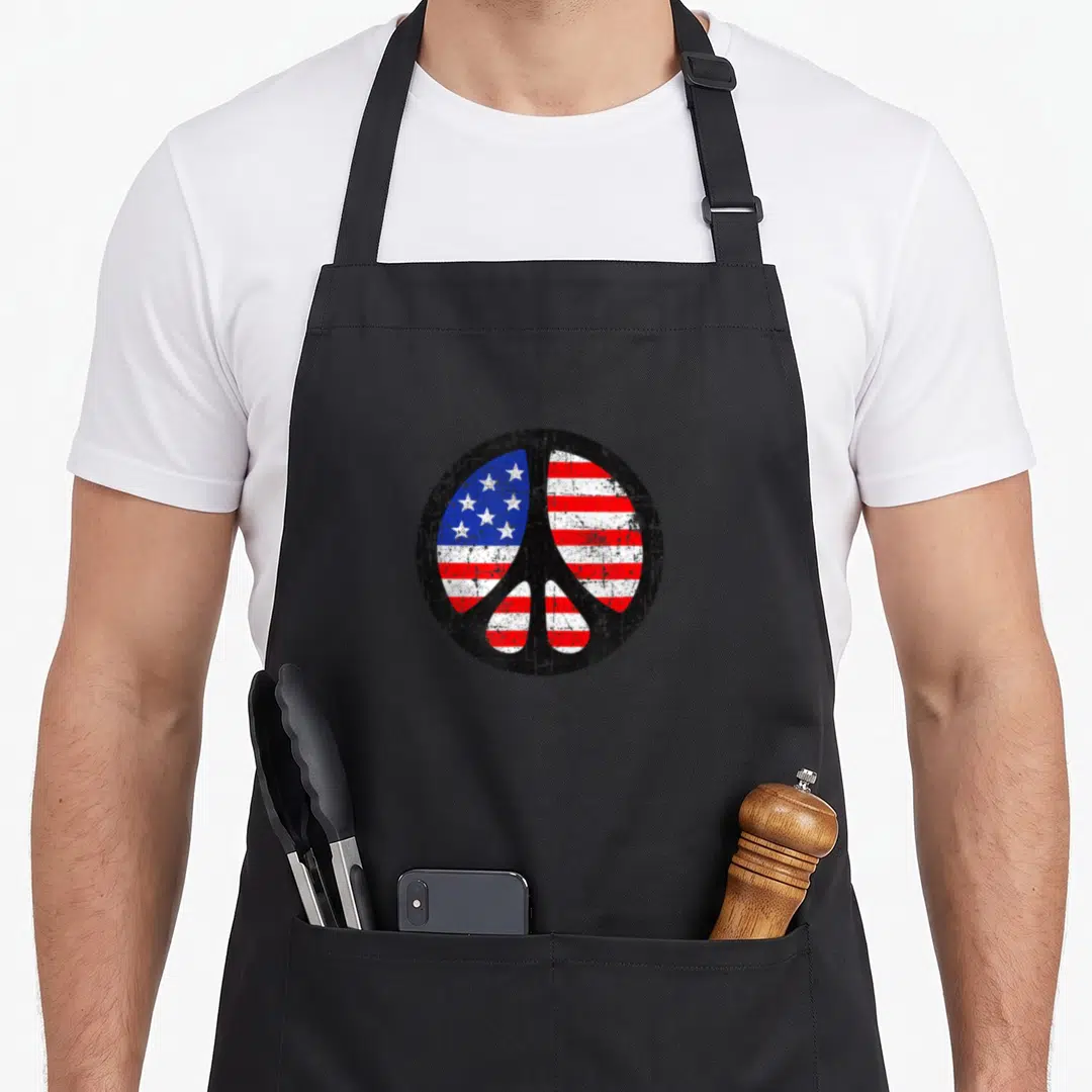 Peace fourth of july aprons - Distressed peace symbol filled with red white and blue US flag stars and stripes — shown on a black cotton canvas apron against a white background