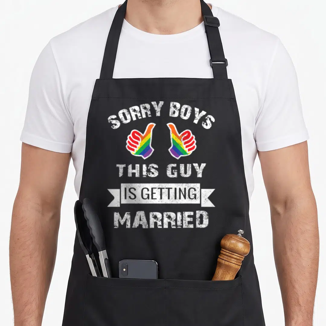 Lgbt hen apron - Rainbow thumbs up hands with sorry boys this guy is getting married distressed text — shown on a black cotton canvas apron against a white background