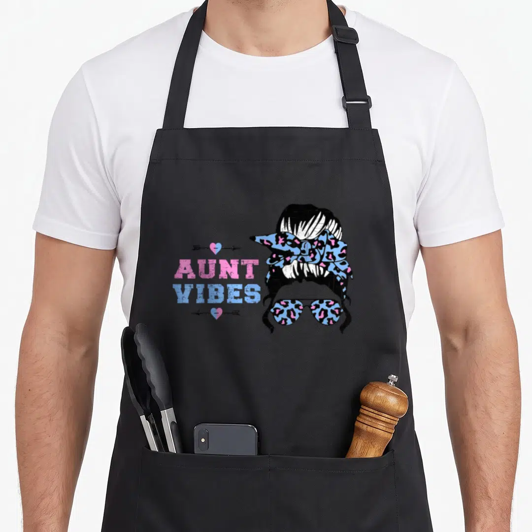Keeper novelty apron - AUNT VIBES text with woman silhouette wearing leopard print sunglasses and bun in pink blue black — shown on a black cotton canvas apron against a white background