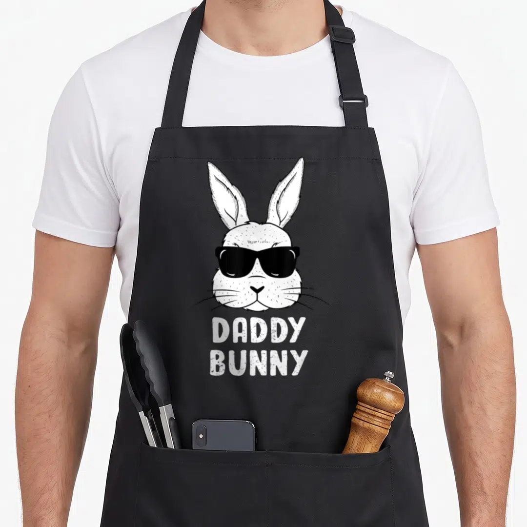 Daddy ear easter bunny aprons - White bunny head with black sunglasses and stacked Daddy Bunny text in line art style — shown on a black cotton canvas apron against a white background