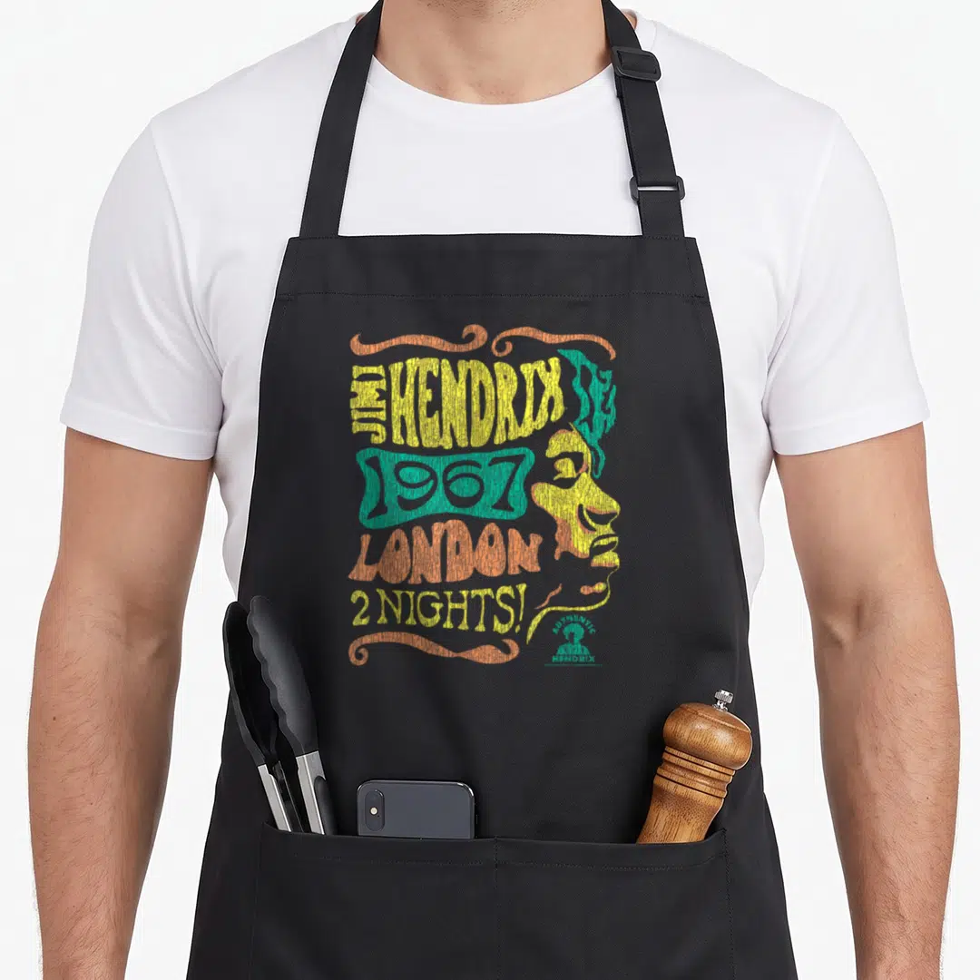 Jimi london aprons - Retro 1967 London concert text with yellow and teal male profile and decorative swirls — shown on a black cotton canvas apron against a white background