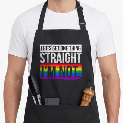 Lgbt straight apron - Stacked white text reading Lets Get One Thing Straight Im Not over a rainbow brushstroke — shown on a black cotton canvas apron against a white background