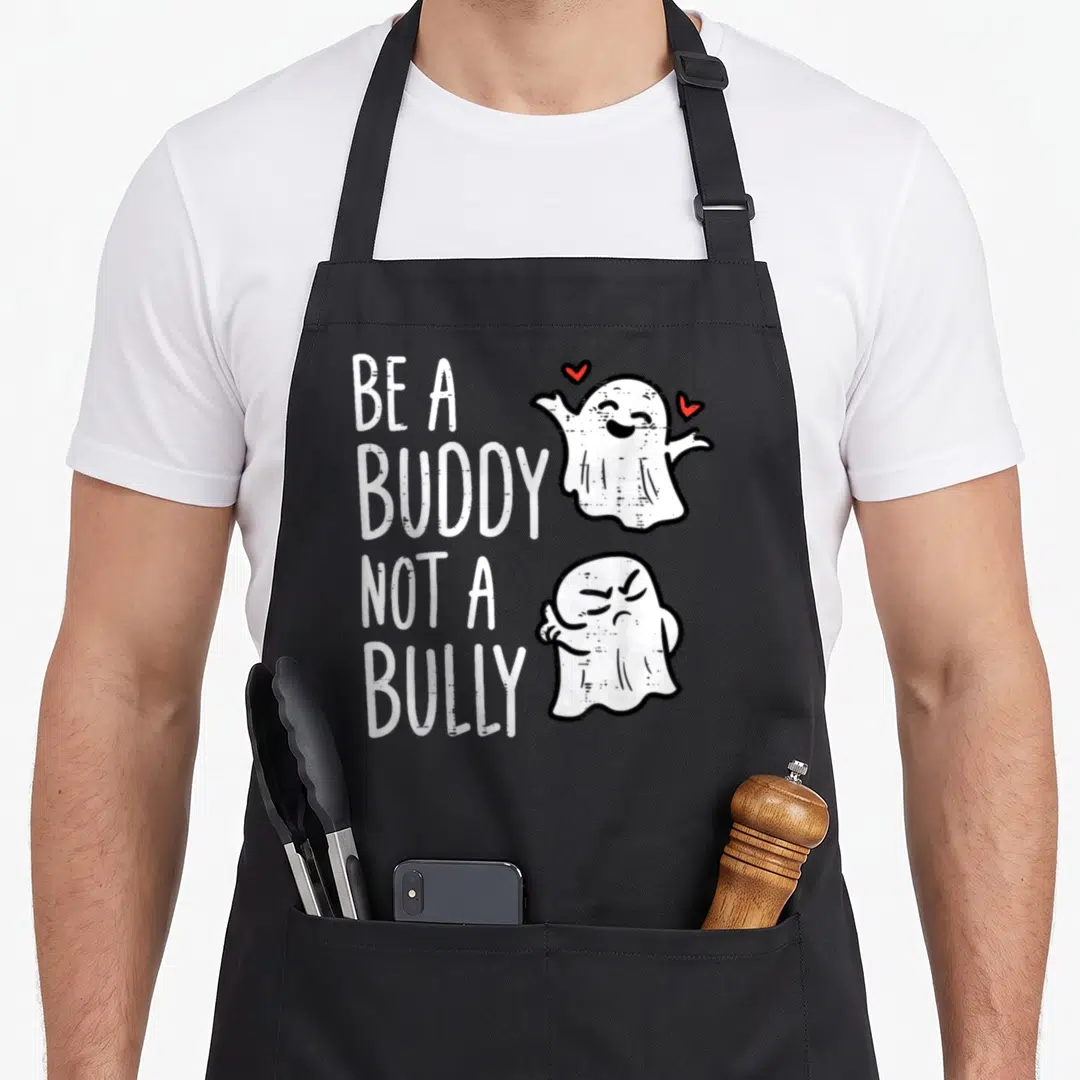 Anti buddy aprons - Be A Buddy Not A Bully text with happy and angry white ghosts and red hearts — shown on a black cotton canvas apron against a white background
