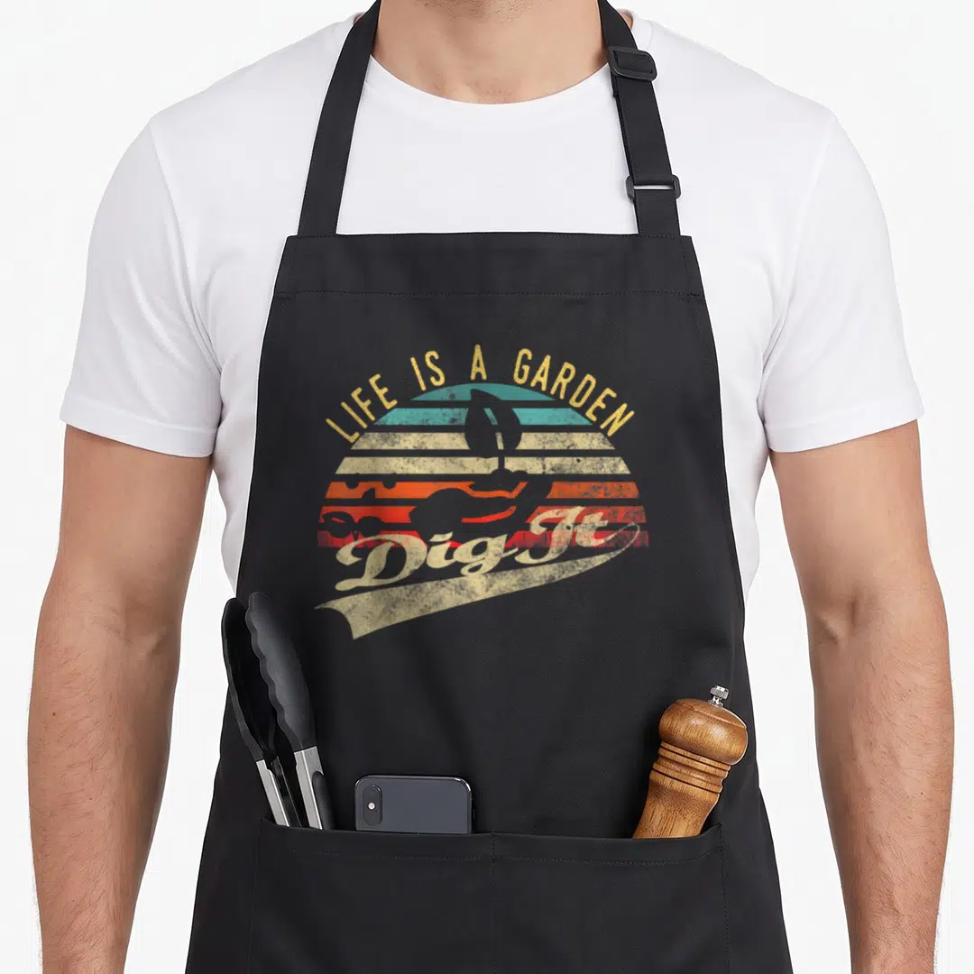 Garden farmer apron - Retro shovel silhouette against yellow teal orange red striped sunset with LIFE IS A GARDEN Dig — shown on a black cotton canvas apron against a white background