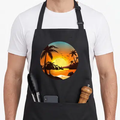 Tropical sunset tree apron - Cartoon sunset circle with black palm trees, birds, and mountains on orange blue gradient — shown on a black cotton canvas apron against a white background