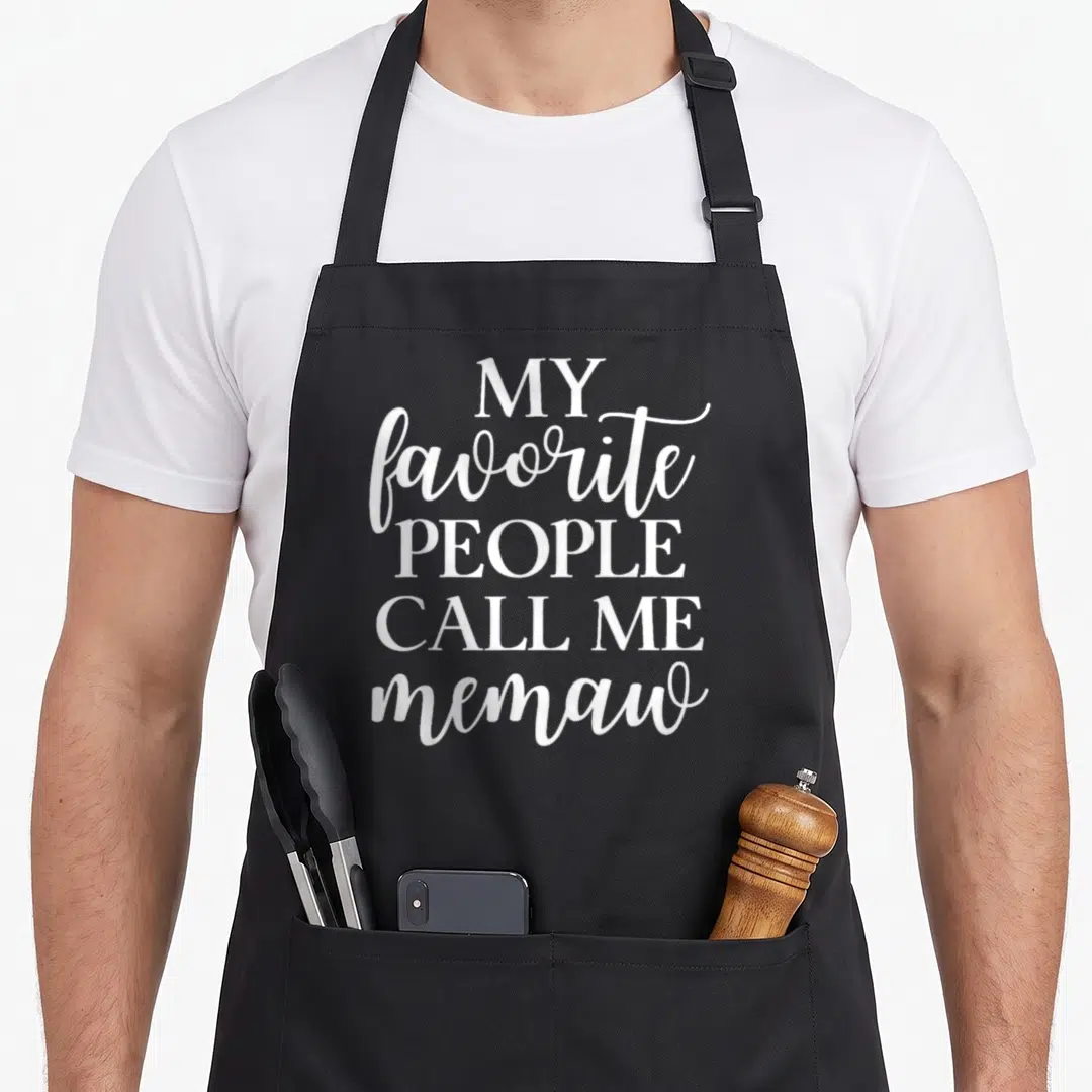 Call memaw apron - White stacked text reading My favorite people call me memaw in mixed fonts — shown on a black cotton canvas apron against a white background