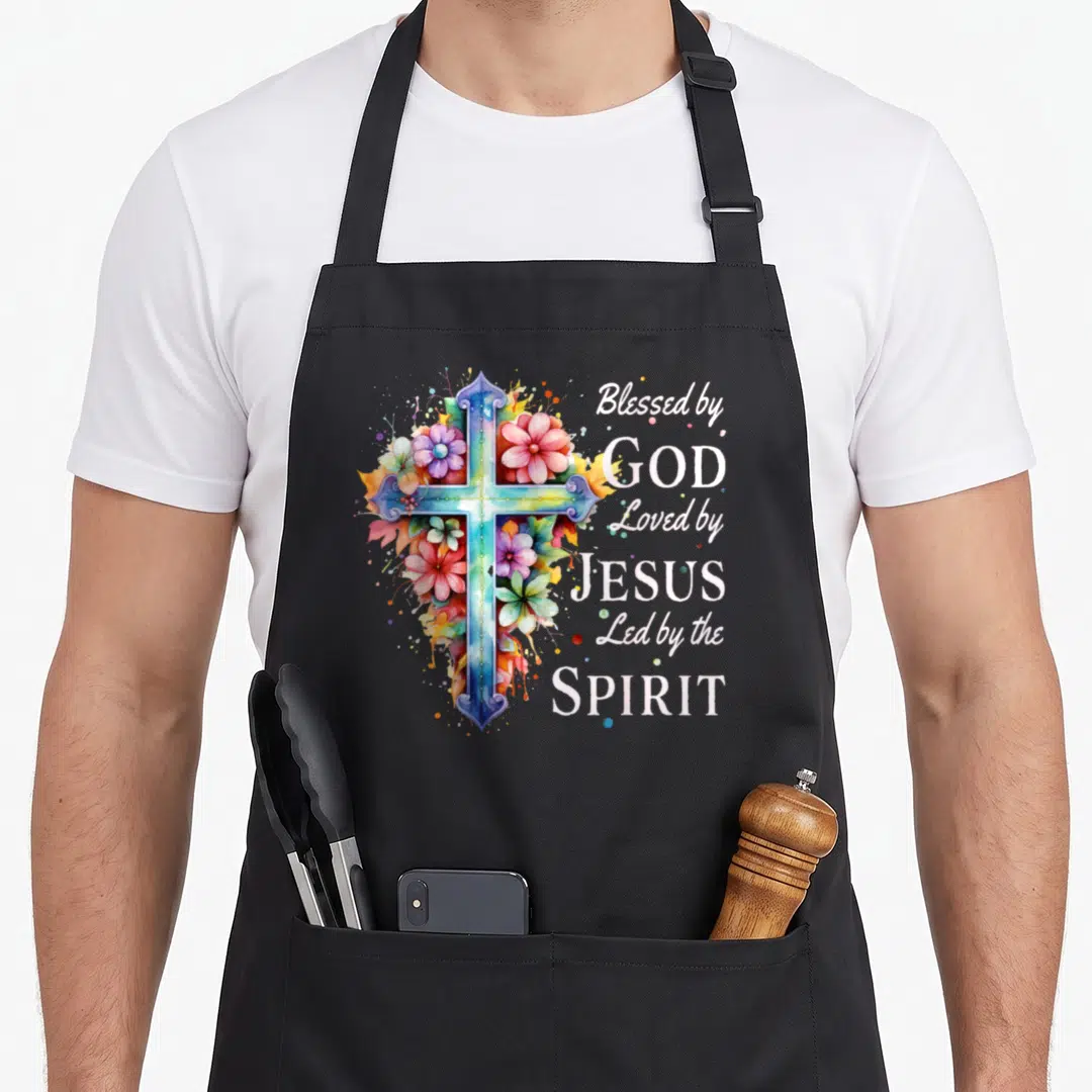 God floral apron - Watercolor cross with pink flowers and white text reading Blessed by God Loved by Jesus Led — shown on a black cotton canvas apron against a white background