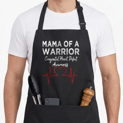 Chd mama apron - Mama of a Warrior text and red heartbeat line with heart shape — shown on a black cotton canvas apron against a white background