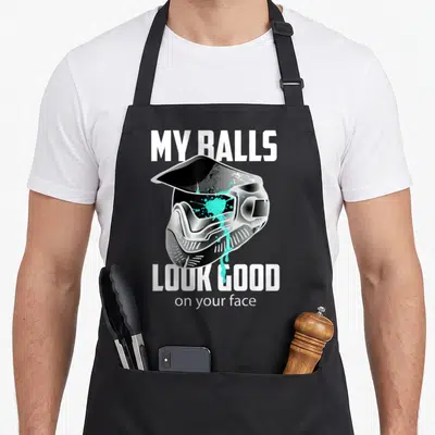Ball shooting apron - Paintball mask with cyan splatter and text MY BALLS LOOK GOOD on your face — shown on a black cotton canvas apron against a white background